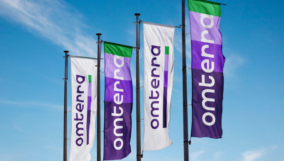 Flags with the omterra logo in purple and green against a blue sky